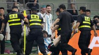Selihai-lihainya menghindar, akhirnya kena tangkap juga. Messi memerhatikan penyusup lapangan yang sudah memeluk dirinya itu digelandang keluar lapangan. Foto: AP/Mark Schiefelbein