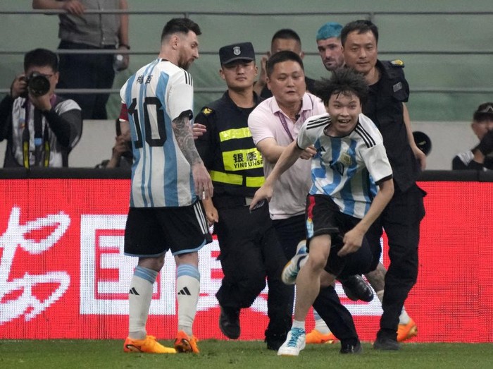 Argentinas Lionel Messi, left, watches as security officers pursue a fan during play on the field in their friendly soccer match against Australia at Workers Stadium in Beijing, Thursday, June 15, 2023. (AP Photo/Mark Schiefelbein)