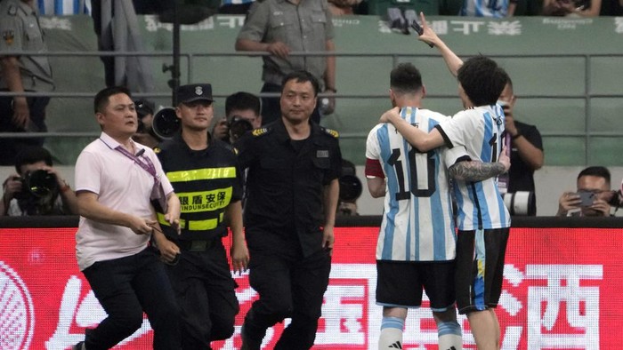 Security officers pursue a fan as he hugs Argentina's Lionel Messi during play on the field in their friendly soccer match against Australia at Workers' Stadium in Beijing, Thursday, June 15, 2023. (AP Photo/Mark Schiefelbein)