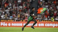 Penggemar itu berlari ke arah Ronaldo sambil membawa bendera Portugal. (Foto: AFP/PATRICIA DE MELO MOREIRA)