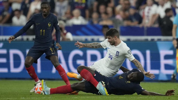 France's Dayot Upamecano, right, and Greece's Taxiarchis Fountas, centre, challenge for the ball during the Euro 2024 group B qualifying soccer match between France and Greece at the Stade de France, outside Paris, Monday, June 19, 2023. (AP Photo/Christophe Ena)