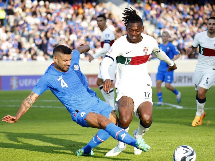 Gol Ronaldo Bawa Portugal Menang Dramatis Atas Islandia Iceland's Guolaugur Victor Palsson challenges Portugal's Rafael Leao during the Euro 2024 group J qualifying soccer match between Iceland and Portugal in Reykjavík, Iceland, Tuesday, June 20, 2023. (AP Photo/Brynjar Gunnarsson)