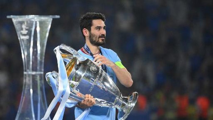 Manchester Citys German midfielder #8 Ilkay Gundogan carries the European Cup trophy over to his teammates as they celebrate winning the UEFA Champions League final football match between Inter Milan and Manchester City at the Ataturk Olympic Stadium in Istanbul, on June 10, 2023. (Photo by FRANCK FIFE / AFP)