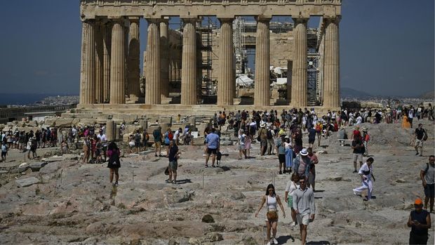 Tourists walk in front of the Parthenon Temple as they visit the Acropolis  archaeological site in Athens on June 14, 2023. 