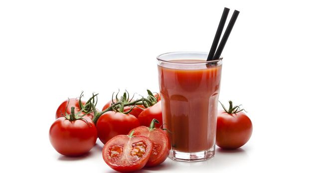 Front view of a glass filled with fresh tomato juice shot on white background. Beside the glass are ripe organic tomatoes placed directly on the backdrop. Two black drinking straws are in the glass. Predominant colors are red and white. High key DSRL studio photo taken with Canon EOS 5D Mk II and Canon EF 100mm f/2.8L Macro IS USM