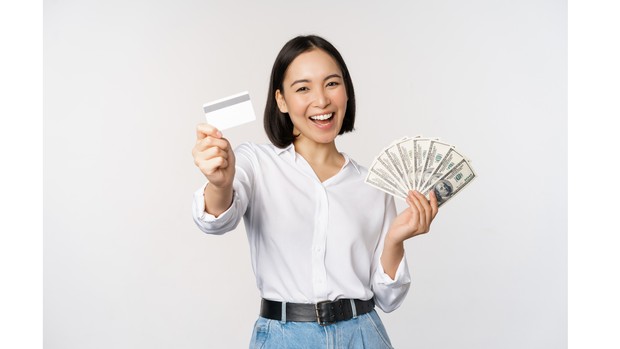 Ilustrasi seorang perempuan memegang uang dan kartu ATM.