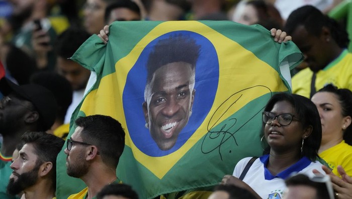 Brazil supporters hold the flag featuring Brazils Vinicius Junior during the international friendly soccer match between Brazil and Senegal, at the Alvalade Stadium in Lisbon, Portugal, Tuesday, June 20, 2023. (AP Photo/Armando Franca)