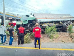Truk Boks Muat Air Mineral Kemasan Terguling di Gerbang Tol Waru