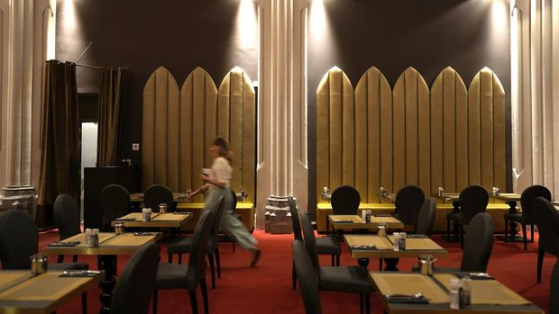 A woman walks through the dining room of the Martin's Patershof hotel in the center of Mechelen, Belgium, Monday, June 19, 2023. Across Europe, the continent that nurtured Christianity for most of two millennia, many churches, convents, beguinages and chapels stand empty as faith and church attendance have dwindled over the past half century. Many are now been repurposed to preserve their historical and architectural relevance, while others have opened up to non-religious activities to expand their use. (AP Photo/Virginia Mayo)