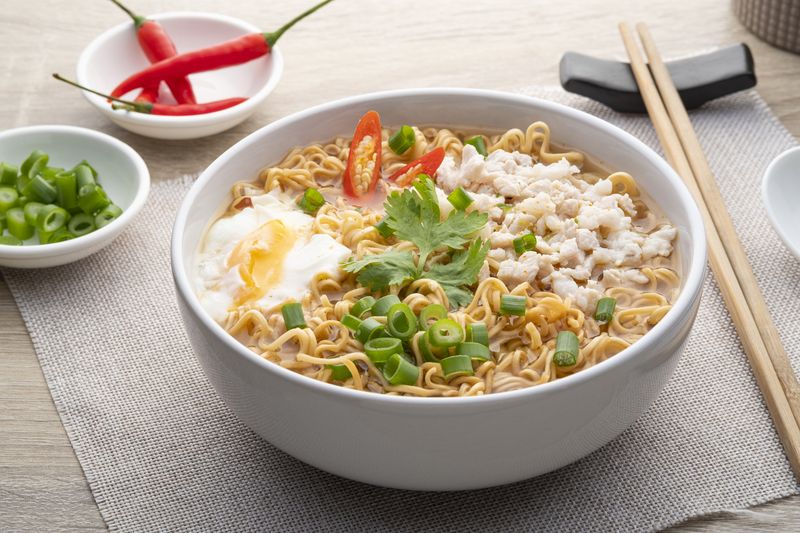 1398323127 Instant noodle soup with minced pork and boiled egg in white bowl on wood table