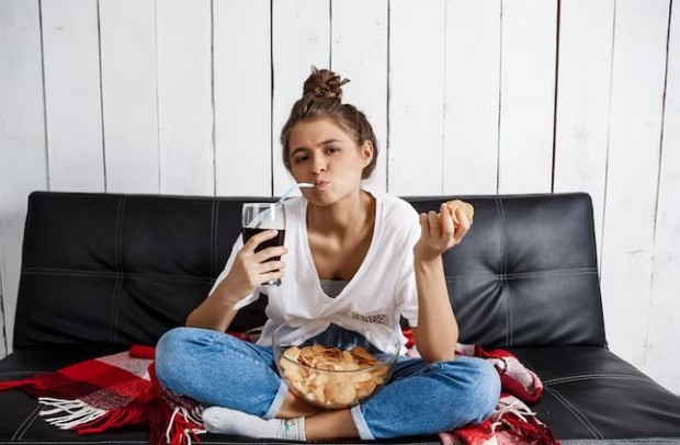 Perempuan makan sambil menonton tv