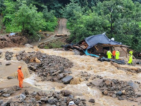 This handout photo taken and released on July 15, 2023 by the Gyeongbuk Fire Service Headquarters shows South Korean emergency workers searching for survivors at a house destroyed by flood waters after heavy rains in Yecheon. Seven people have died and three have gone missing amid torrential rains that have flooded many parts of  South Korea, forcing thousands of people to evacuate from homes amid the warning of an overflowing dam. (Photo by Handout / Gyeongbuk Fire Service Headquarters / AFP) / RESTRICTED TO EDITORIAL USE - MANDATORY CREDIT 