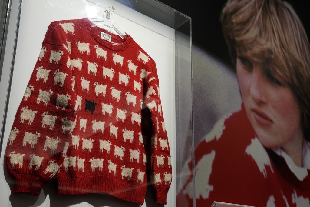 A Sotheby's employee looks at the historic Princess Diana black sheep jumper at the auction house Sotheby's in London, Monday, July 17, 2023. The 'Worn on Several Occasions & Adored by the Fashion Icon' jumper will be on auction headlining Sotheby's inaugural fashion icons sale in New York this September at an Estimate of $50,000 – 80,000, 38,000-61,000 pounds. (AP Photo/Frank Augstein)