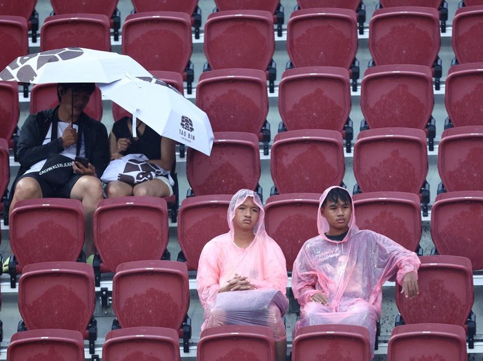Soccer Football - Pre Season Friendly - Leicester City v Tottenham Hotspur - Rajamangala National Stadium, Bangkok, Thailand - July 23, 2023 Fans in rain coats inside the stadium as the match is cancelled due to bad weather REUTERS/Athit Perawongmetha