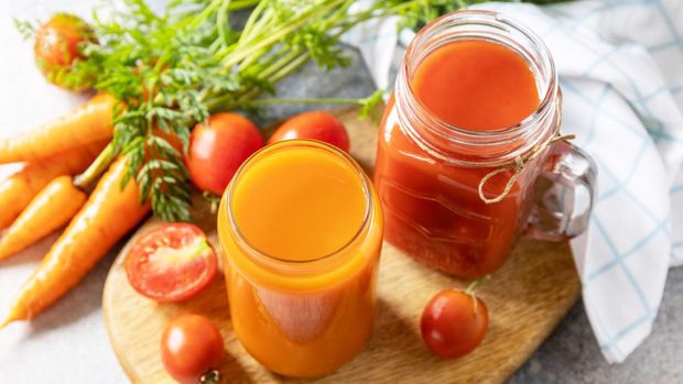 Vitamins drinks juice carrot and tomato. Tomato and carrot juice in a glasses on a stone table. Healthy lifestyle.