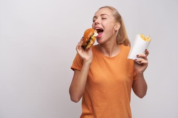 Nafsu makan/ foto: Freepik/ nakaridore Perempuan sedang makan burger