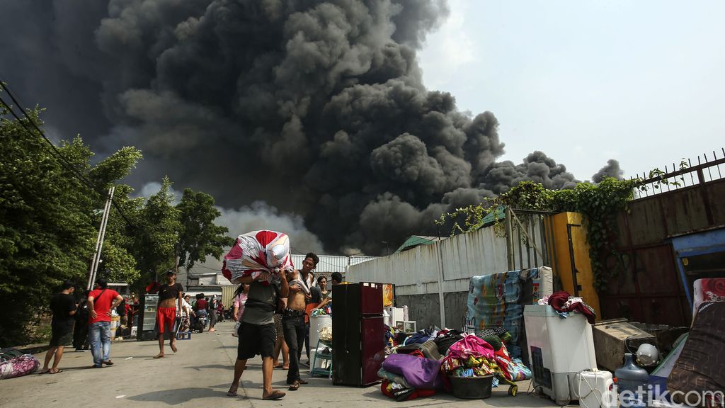 Warga berupaya mengevakuasi barang dari kobaran api di Gang Manggis Jalan Kapuk Utara II, Kapuk Muara, Jakarta Utara, Minggu (30/7/2023).