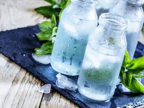 Very cold mineral water with ice in a misted glass bottles, dark background, selective focus