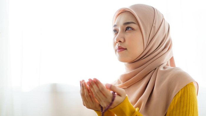 ilustrasi perempuan muslim berdoa Beautiful Asian young Muslim woman sit on the floor in her house and praying for a holy god - Allah in Islam believe.