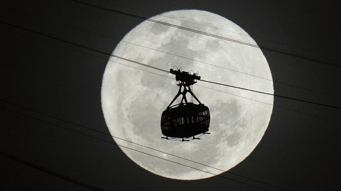 A cable car moves towards Sugar Loaf mountain as a supermoon rises on the night sky in Rio de Janeiro, Brazil, Tuesday, Aug 1, 2023. (AP Photo/Silvia Izquierdo)