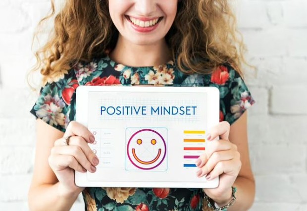 Perempuan memegang kertas bertuliskan positive mindset