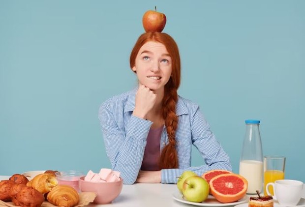 Perempuan sedang duduk di meja makan terlihat bingung