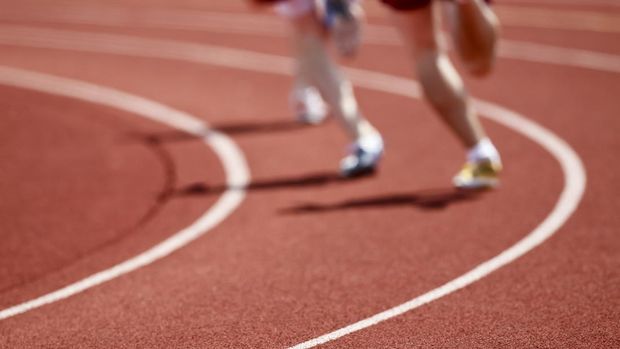 A group of runners rounds a curve on an all weather running track.  Shot with a 400mm lens at 2.8 to produce a very shallow depth of field.  The rough surface of the track combined with the shallow depth of field make a great pattern.