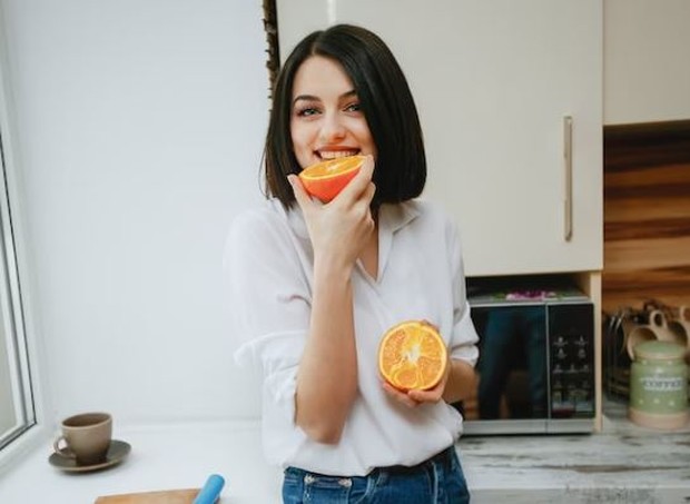 Perempuan sedang makan jeruk