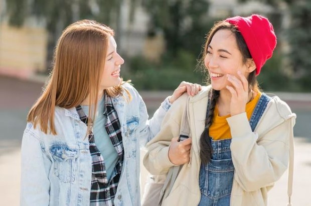 Dua perempuan sedang mengobrol sambil tertawa