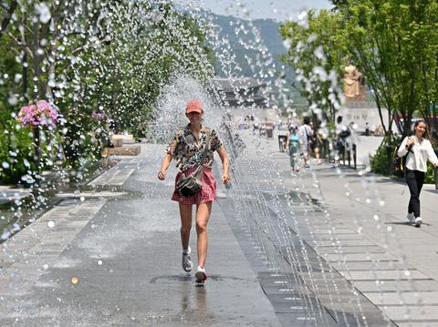 A woman walks through a water tunnel to cool off in the central Gwanghwamun area of Seoul on June 19, 2023, as a heat wave advisory has been issued by the South Korean government. (Photo by Jung Yeon-je / AFP) (Photo by JUNG YEON-JE/AFP via Getty Images)