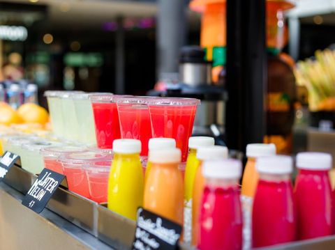 Close up color image depicting freshly made fruit juices and smoothies on display in a row and for sale at a food and drink market in London, UK. Selective focus on the plastic cups containing the fresh smoothies. Room for copy space.