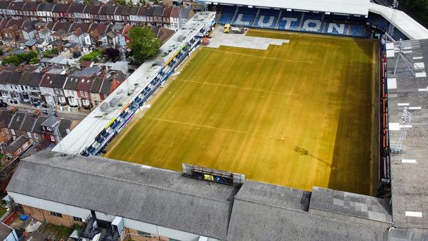 An aerial picture taken on May 31, 2023 shows Luton Town's Kenilworth Road stadium, in Luton, as members of the ground staff remove the pitch lines and cover the grass during the end of season works. Luton's football team completed a fairytale journey to the Premier League after beating Coventry on penalties in the Championship playoff final at Wembley last week on May 27, 2023. Financial experts estimate promotion to world football's most watched league to be worth around 170 million ($210 million) for a club that have been through turmoil since they last played in the top flight 31 years ago. Luton are the first club to go from the fifth tier to the top flight in the Premier League era. (Photo by Justin TALLIS / AFP)