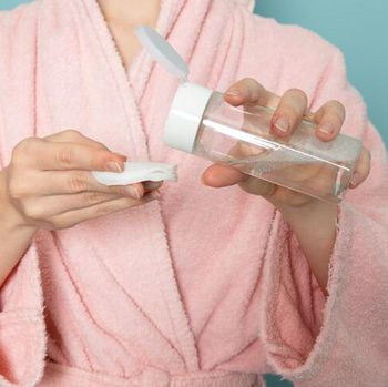Foto seorang perempuan dengan botol toner dan kapas.