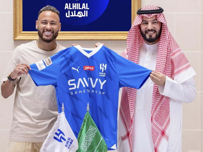 In this photo provided Al Hilal club media center, Neymar holds a Al Hilal shirt after signing with Chairman of the Board of Directors of Al Hilal, Fahad Bin Saad Bin Nafel, in Paris, France, Tuesday, Aug. 15, 2023. (Al Hilal Club Media Center via AP)