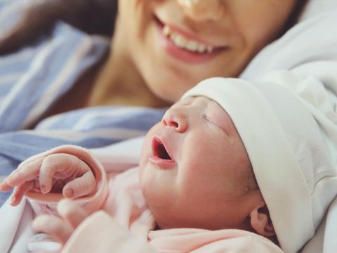 Pregnant young woman lying on the bed in delivery room. Side view of happy pregnant female resting on bed in hospital ward. Healthcare and pregnancy concept