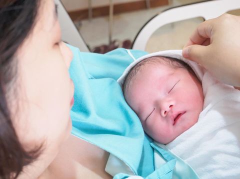 Pregnant young woman lying on the bed in delivery room. Side view of happy pregnant female resting on bed in hospital ward. Healthcare and pregnancy concept