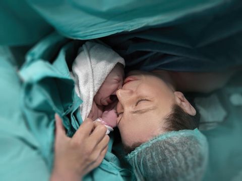 Pregnant young woman lying on the bed in delivery room. Side view of happy pregnant female resting on bed in hospital ward. Healthcare and pregnancy concept