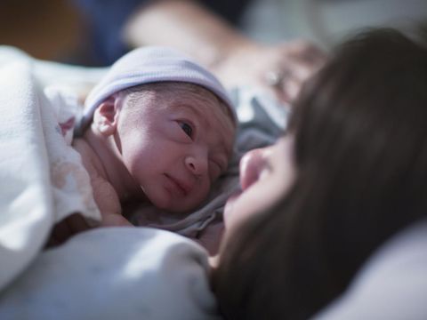 Pregnant young woman lying on the bed in delivery room. Side view of happy pregnant female resting on bed in hospital ward. Healthcare and pregnancy concept