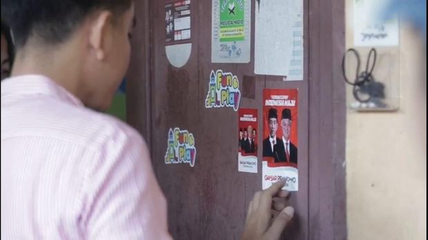 Wali Kota Solo Gibran Rakabuming Raka, menempel stiker bergambar Jokowi-Ganjar saat blusukan di RW 11 Joyosuran, Kecamatan Pasar Kliwon, Kota Solo, Sabtu (19/8/2023).