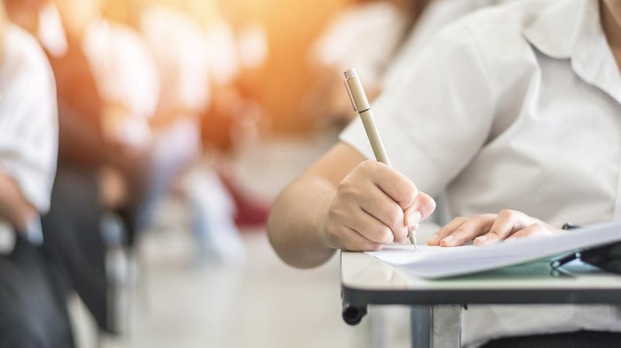 Exam with school student having a educational test, thinking hard, writing answer in classroom for  university education admission and world literacy day concept