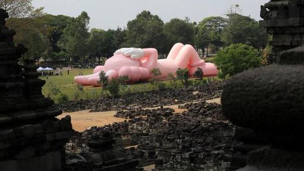 Instalasi seni berukuran raksasa yang dikenal sebagai KAWS, karya seniman Amerika Brian Donnelly terlihat menghiasi Candi Prambanan, Yogyakarta, Jawa Tengah. (DEVI RAHMAN / AFP)