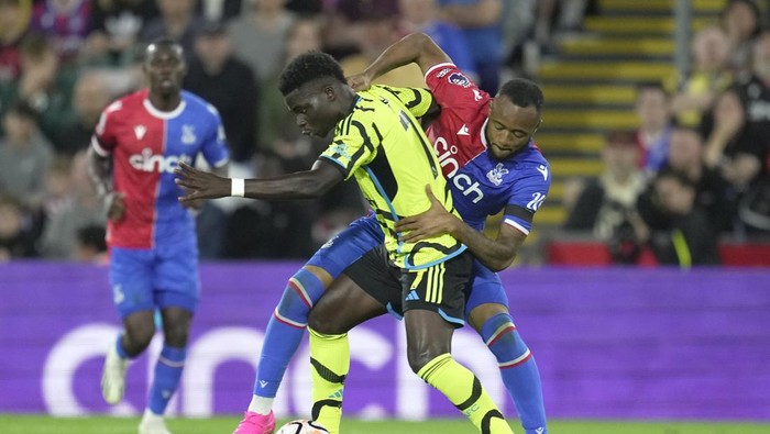 Arsenals Bukayo Saka, center left, battles for control of the ball against Crystal Palaces Jordan Ayew during the Premier League soccer match between Crystal Palace and Arsenal at Selhurst Park, in London, England, Monday, Aug. 21, 2023. (AP Photo/Kin Cheung)