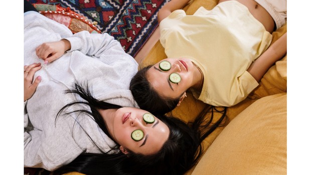 Foto dua orang perempuan yang tengah memakai skincare untuk kulit wajah mereka.