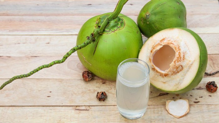 Fresh Coconut Water Drink in glass with coconut leaf on wooden  background