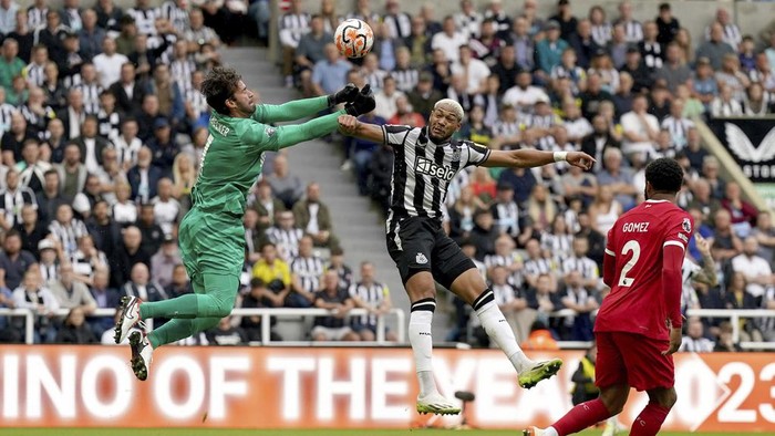 Liverpools Alisson Becker punches the ball away from Newcastle Uniteds Joelinton during the English Premier League soccer match between Newcastle United and Liverpool at St. James Park, in Newcastle upon Tyne, England, Sunday Aug. 27, 2023. (Owen Humphreys/PA via AP)