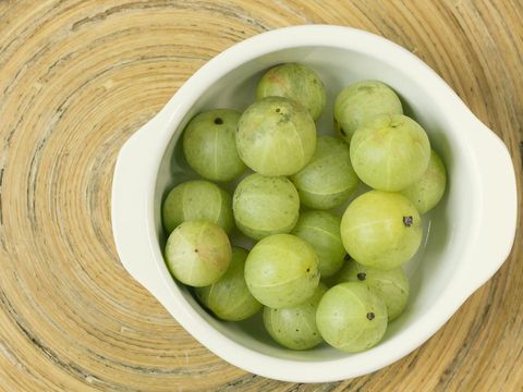 Gooseberries in a ceramic bowl close-up on a light background.