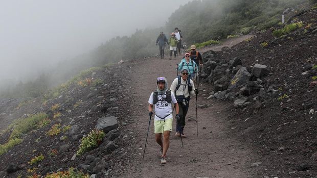 This photo taken on August 31, 2023 shows visitors descending the slopes of Mount Fuji, Japan's highest peak at 3,776 meters (12,388 feet). With its millions of visitors every year and the buses, supply trucks, noodle shops and fridge magnets, Mount Fuji is no longer the peaceful, nature-filled pilgrimage site it once was. (Photo by Mathias CENA / AFP) / TO GO WITH Japan-leisure-environment,FOCUS by Mathias CENA