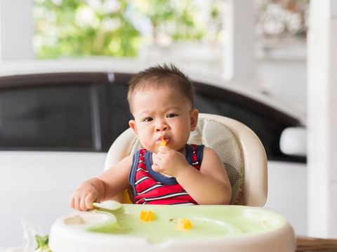 the baby learns to eat by himself. he can use spoon well. so he is very happy (focus at his face)