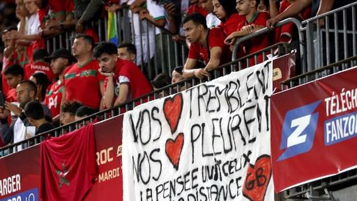 Fans display a sign during the international friendly football match between Morocco and Burkina Faso at the Stade Bollaert-Delelis in Lens, northern France, on September 12, 2023. The Royal Moroccan Football Federation (FRMF) has announced that the proceeds from the match will be donated to help support the victims of the recent earthquake that struck several regions in Morocco on September 8, 2023. (Photo by Ayoub Benkarroum / AFP)