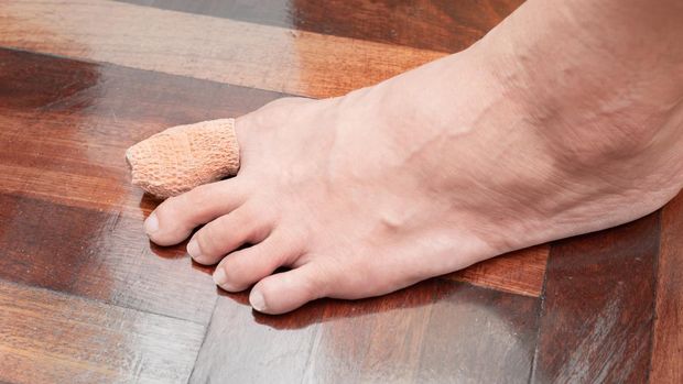 Close up of one bare human female feet with a wounded big toe healed with bandage for medical care. accident or safety first concept